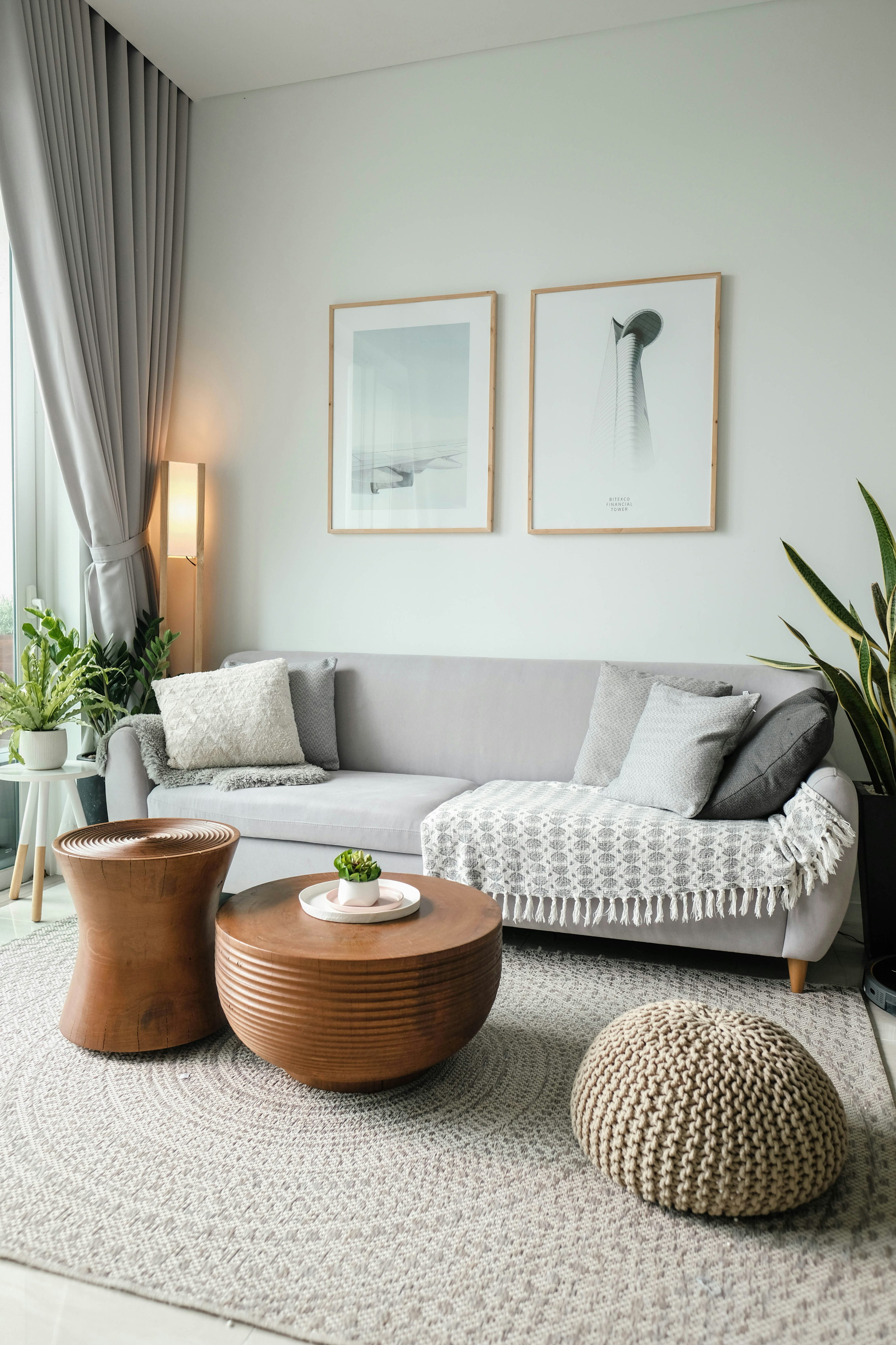 Przytulny salon z jasną sofą, roślinami i drewnianymi stolikami
